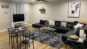 A modern living room with a black leather sofa, a coffee table, a TV, and a ceiling fan.