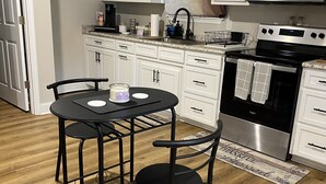 A modern kitchen with white cabinets, a black stove, and a dining table with chairs.
