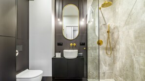 A modern bathroom with a white toilet, a black vanity, a gold showerhead, and a large mirror. - Plac Unii 40 - Comfy Apartments (Gdynia)