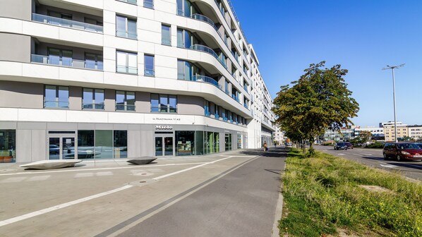 A modern building with multiple floors, large windows, and a visible entrance with glass doors. - Plac Unii 40 - Comfy Apartments (Gdynia)