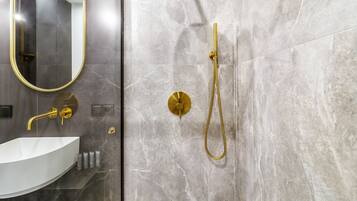 Une salle de bain moderne avec un lavabo blanc, des robinetteries dorées et des murs en marbre.