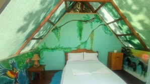 A tent-style room with a bed, a lamp, and a mural of parrots. -  Pirate Drake Beach Hostel (Drake Bay)