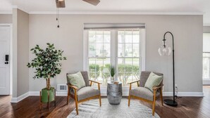 Ein Wohnzimmer mit Deckenventilator, zwei Sesseln, einem Couchtisch, einer Topfpflanze und einer Stehlampe.