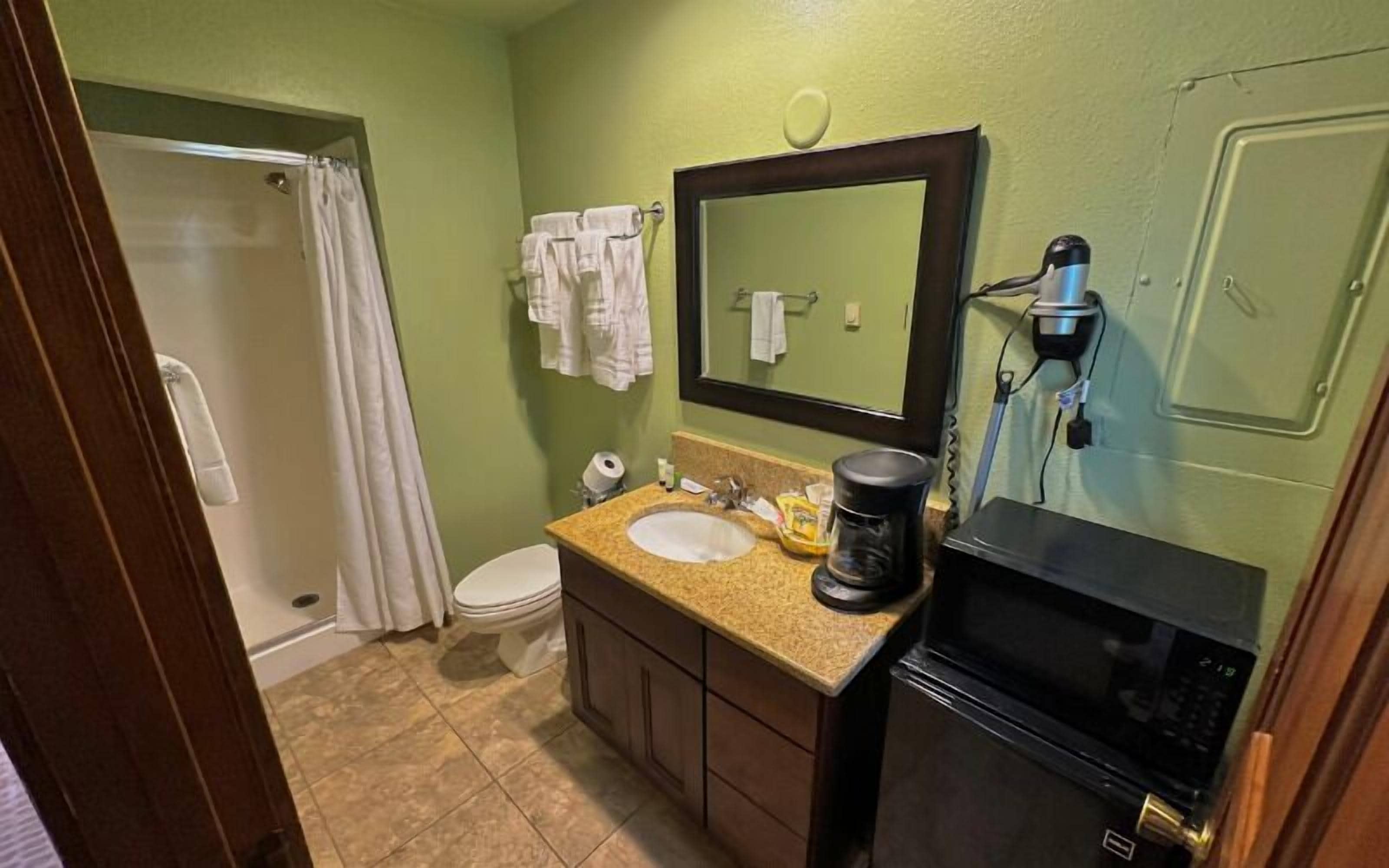 A bathroom with a sink, mirror, toilet, and shower.