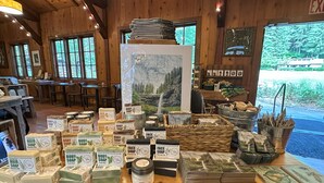A wooden interior with shelves of body and hair soaps, jars, and a display of cards. - Smith Creek Village  (Sublimity)