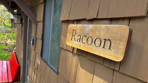 A wooden sign with the word "Racoon" on it, mounted on a building. - Smith Creek Village  (Sublimity)
