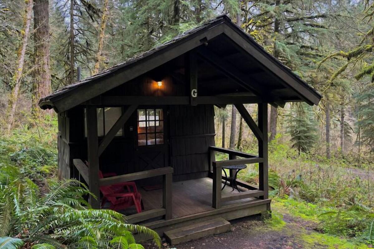 A rustic cabin with a porch, a small table, and a single window.