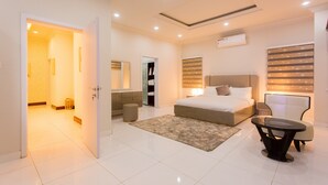 A modern bedroom with a large bed, bedside tables, a desk, and a chair.