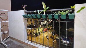 A balcony with potted plants and a view of a busy street at night. - Cozy 1-bedroom condo with AC and WiFi in central Davao City (Davao City)