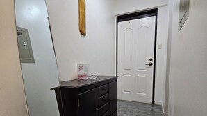 A hallway with a large mirror, a black dresser, and a white door. - Cozy 1-bedroom condo with AC and WiFi in central Davao City (Davao City)