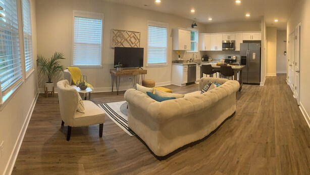 A spacious living area with a sofa, a coffee table, and a TV. There is a kitchen in the background with modern appliances. - 3-bedroom bungalow in charming Easley with AC, WiFi (Easley)