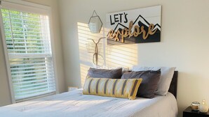 A neatly made bed with striped bedding, a wall-mounted lamp, and a motivational quote. - 3-bedroom bungalow in charming Easley with AC, WiFi (Easley)