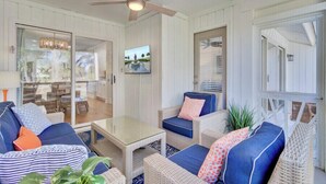 A room with wicker furniture, a ceiling fan, and a glass door leading to an outdoor area.