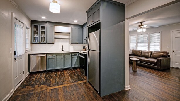 A modern kitchen with grey cabinets, a stainless steel refrigerator, and a wooden floor. - Peaceful Clinton Retreat in Olde Towne (Clinton)