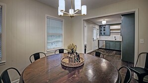 A dining area with a round wooden table, black chairs, a woven centerpiece, and a chandelier. - Peaceful Clinton Retreat in Olde Towne (Clinton)