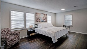 A bedroom with a large bed, two bedside tables, a nightstand, and a chair. - Peaceful Clinton Retreat in Olde Towne (Clinton)