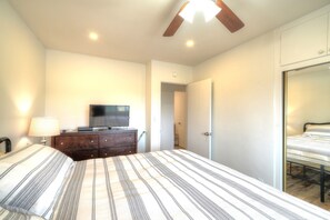 A bedroom with a bed, a television on a dresser, a ceiling fan, and a door leading to another room. - Beautiful 2 bed w/Ocean view - private wifi (Carpinteria)