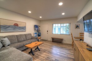 A living room with a gray sofa, wooden coffee table, and a TV on a wooden cabinet.