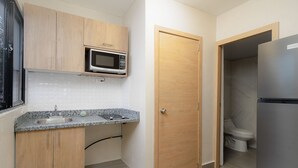 A compact kitchen with wooden cabinets, a microwave, a sink, and a refrigerator.