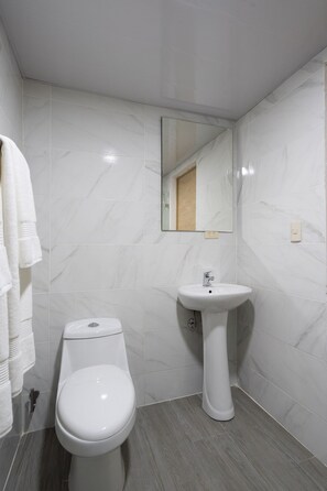 A bathroom with a toilet, sink, and mirror. - Studio in Gazcue: from Colonial Zone & Incipler (Santo Domingo)