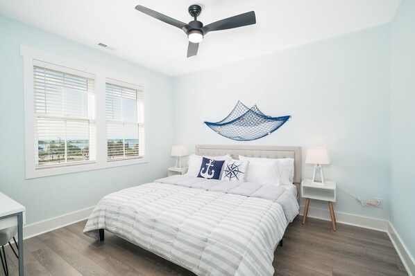 A bedroom with a bed, two bedside tables, a ceiling fan, and a window with blinds. - Crystal Coast Getaway (Beaufort)