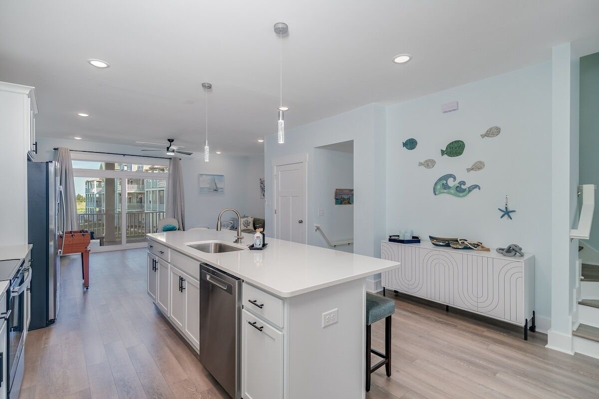 A modern kitchen with a central island, white cabinetry, and a view to the outside.