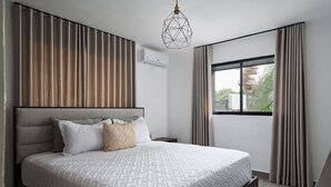 A modern bedroom with a large bed, a geometric pendant light, and a window with curtains. - Modern 2BR ·Gazcue · 5min to Monuments · YellowKey (Santo Domingo)