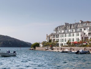 A waterfront property with a row of white buildings, a dock with boats, and a hilly backdrop. - 43 The Salcombe (Salcombe)