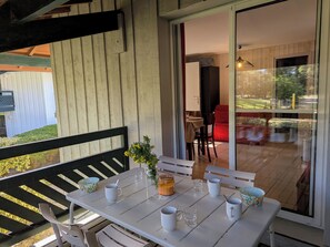 Zona pranzo con tavolo bianco apparecchiata per due, una panca e vista sul patio esterno.