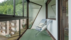 Un balcon agrémenté d’un tapis vert, d’une chaise longue et offrant une vue sur un immeuble doté de balcons.