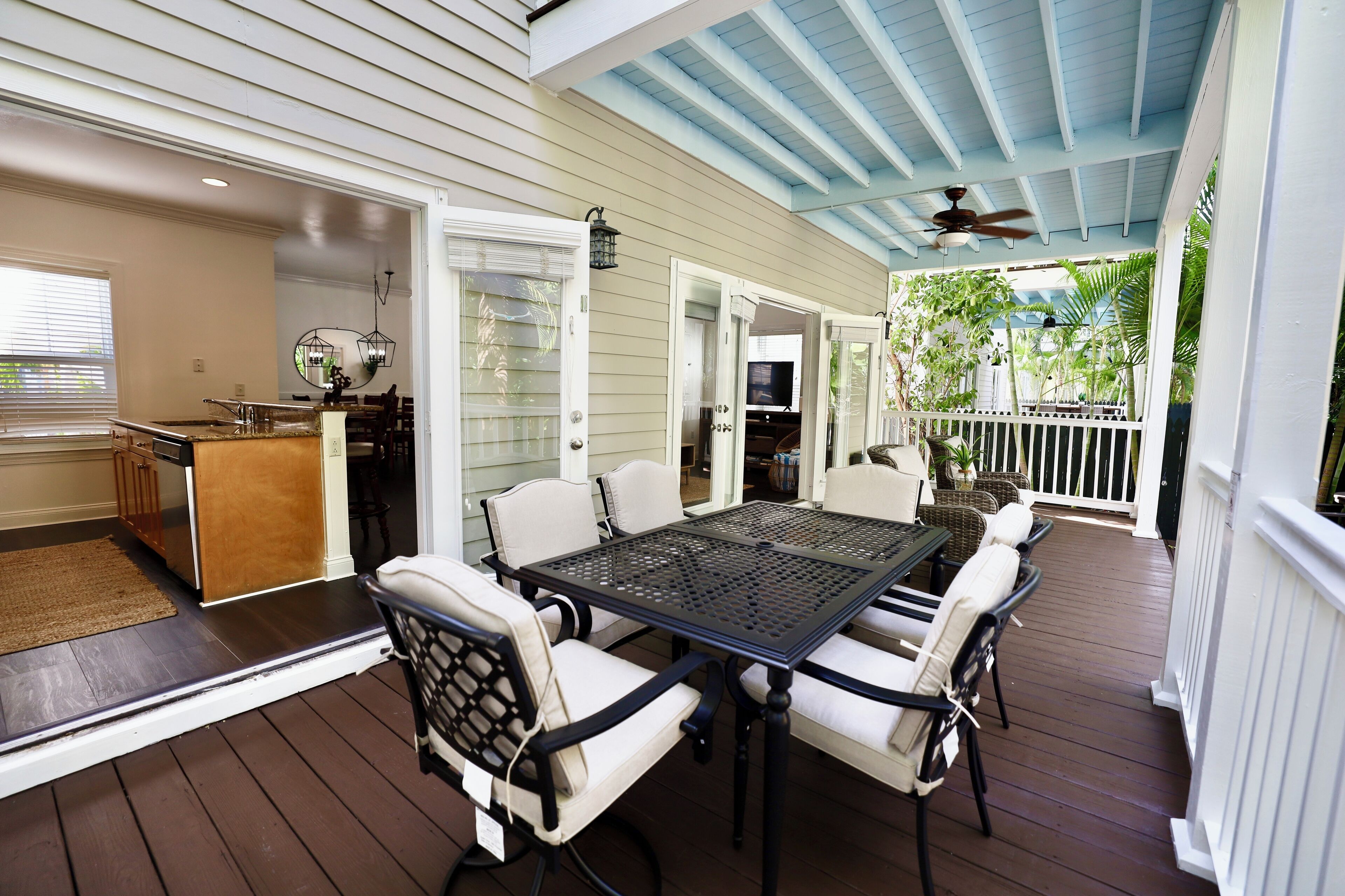 A covered patio with a dining table and chairs, a kitchen area with a counter and appliances, and a view of the outdoors.