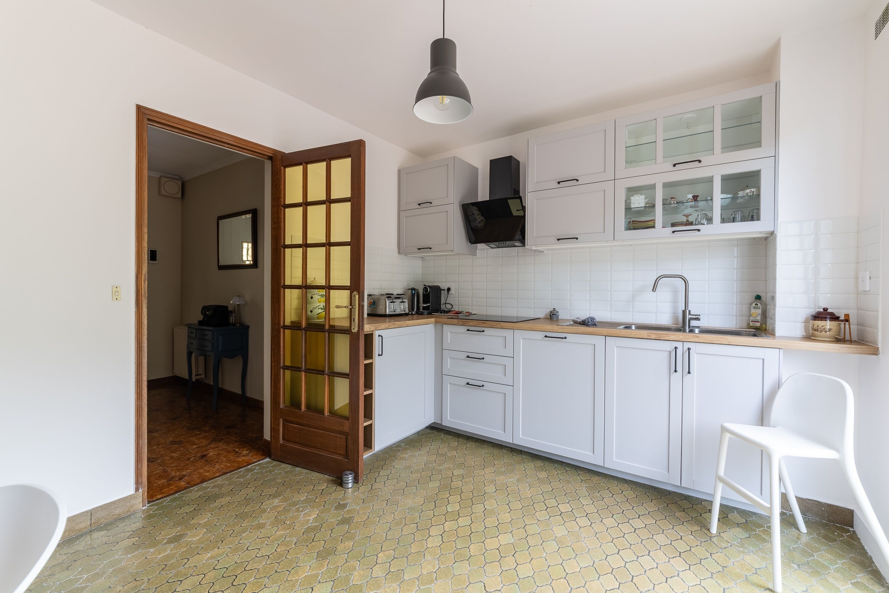 A modern kitchen with white cabinets, a wooden countertop, and a tiled backsplash.