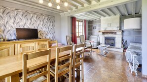 Amplia sala de estar con una mesa de comedor de madera, sillas, chimenea y televisor.