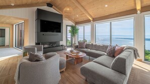 Un salon moderne avec une cheminée, de grandes fenêtres et une vue sur la mer.