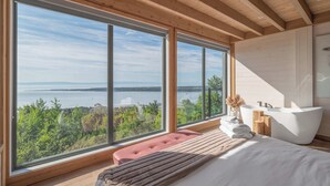Une chambre avec une grande fenêtre, une baignoire et un banc.