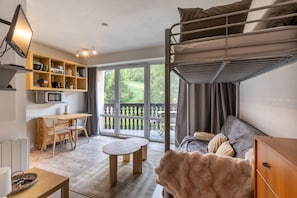 A compact living space with a bunk bed, a desk with shelves, a dining table, and a sofa. - Le Mont Louis - Accès direct remontées mécaniques (Les Angles)