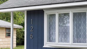 A house with the numbers 126 on its side, a window with white trim, and a covered porch.