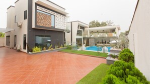 Ein modernes, zweistöckiges Haus mit Swimmingpool, überdachter Terrasse und gepflegtem Rasen.
