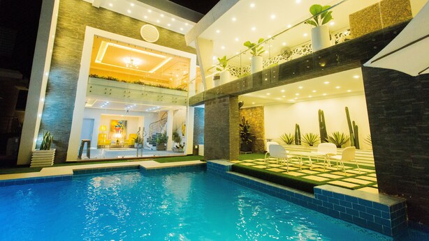 Ein modernes Hotel mit Schwimmbad, heller Innenarchitektur und Sitzgelegenheiten im Freien.