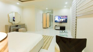 Ein modernes Hotelzimmer mit einem großen Bett, einem Fernseher, einem Schminktisch und einem Spiegel.