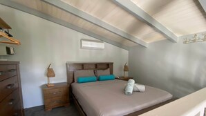 Un dormitorio con una cama de madera, un aparador, una mesita de noche y un ventilador de techo.