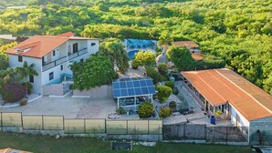 Una casa con un panel solar, piscina y patio cercado.