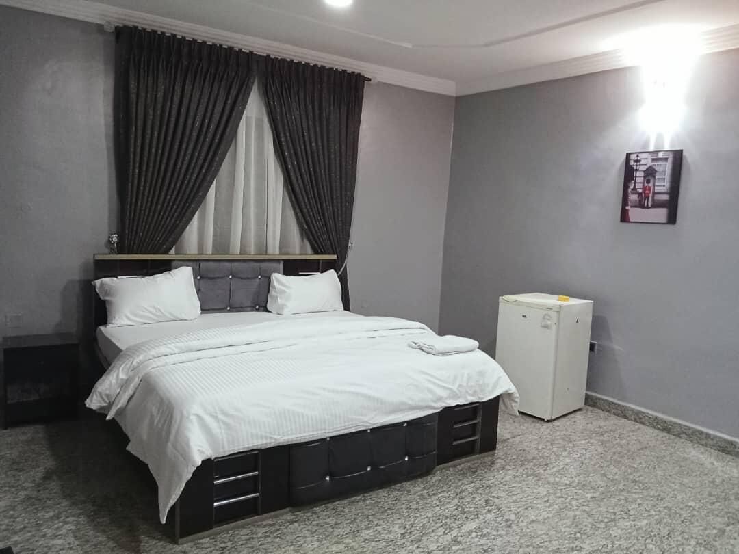 A bedroom with a bed, curtains, a radiator, and a framed picture on the wall.