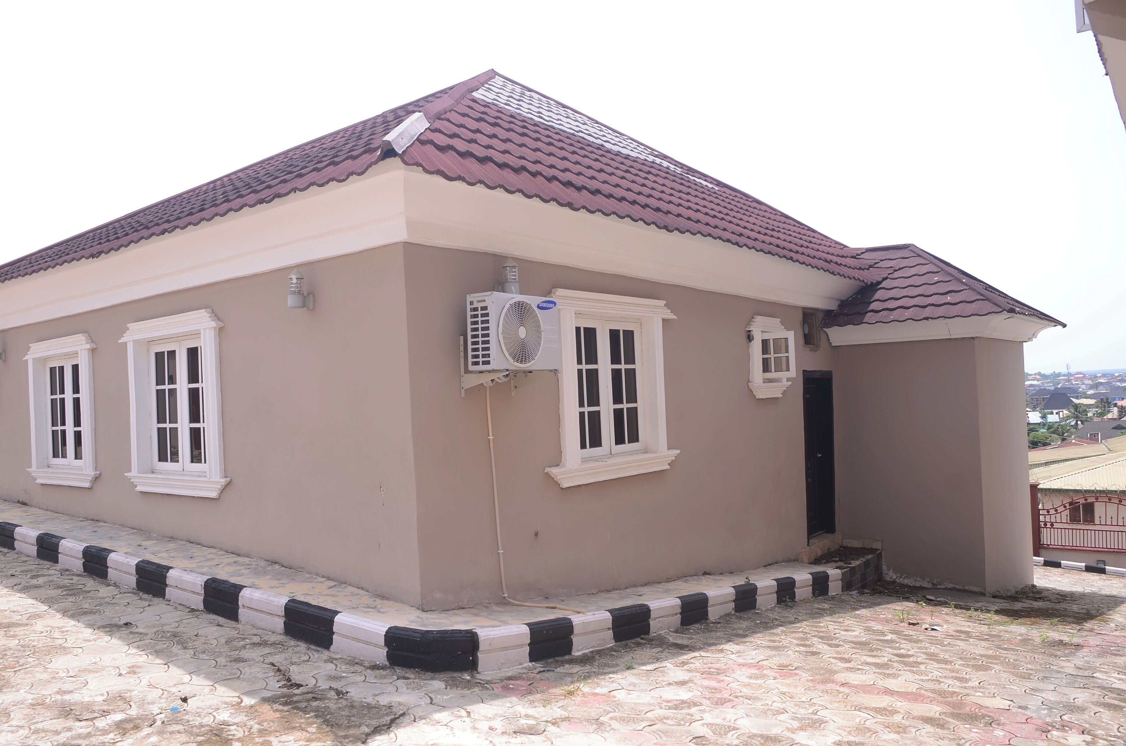 A building with a tiled roof, a small attached structure, and a paved entrance area.