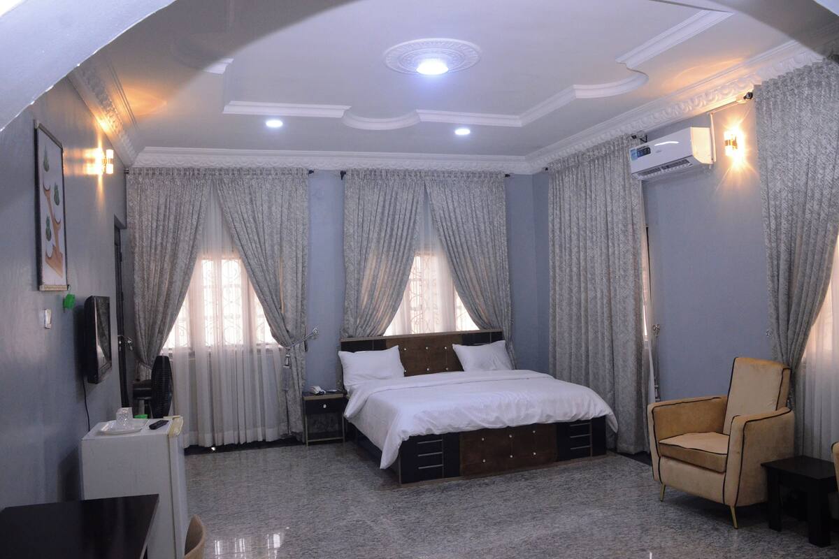 A hotel room with a bed, a chair, a desk, and a TV.
