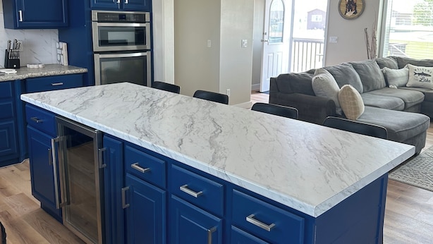 A modern kitchen with blue cabinets, a marble countertop, and stainless steel appliances. - The Reel Deal in Devils Lake with Shop – Boat Launch Nearby (Devils Lake)