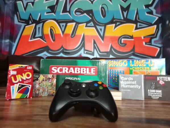 A game controller, Scrabble, UNO, and BINGO LIME-UP on a table.