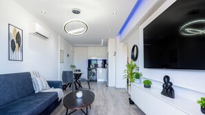 Un saló modern amb un sofà, una taula de centre i un televisor pla muntat a la paret.