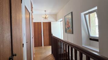 A hallway with wooden doors, a chandelier, a painting, and a window.
