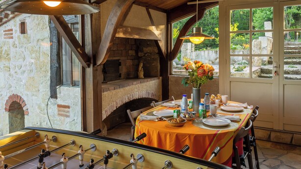 A dining area with a stone fireplace, wooden beams, and a table set for a meal. - Lacoume Saint Jacques (Auch)